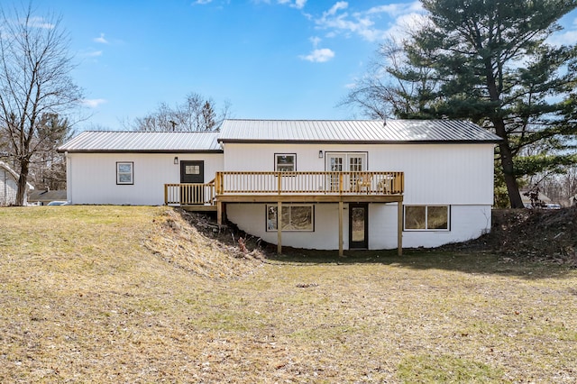 back of house featuring a wooden deck, a yard, and metal roof