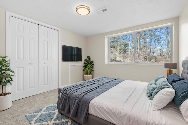 carpeted bedroom with visible vents and a closet