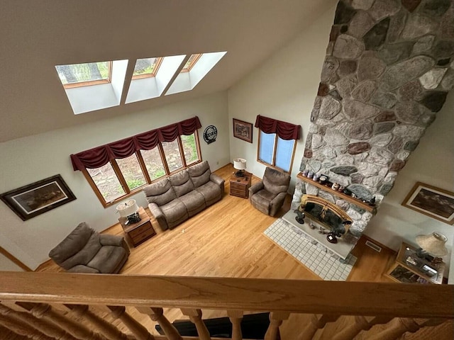 living room featuring a skylight, wood finished floors, visible vents, and high vaulted ceiling