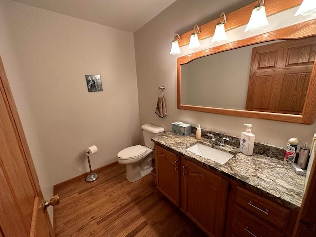 bathroom with vanity, toilet, wood finished floors, and baseboards