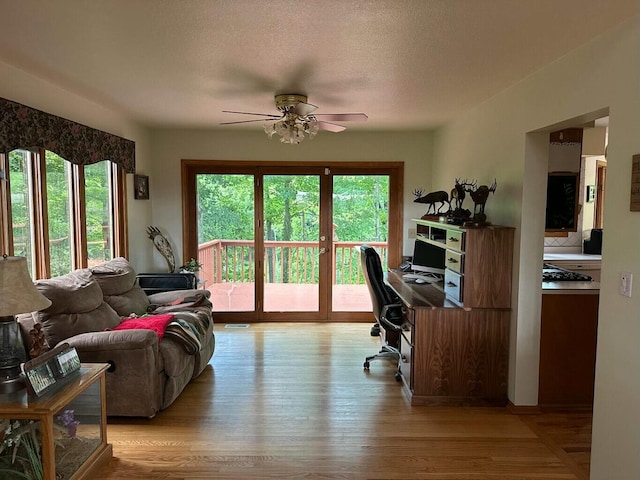 office featuring light wood-type flooring, a textured ceiling, visible vents, and ceiling fan