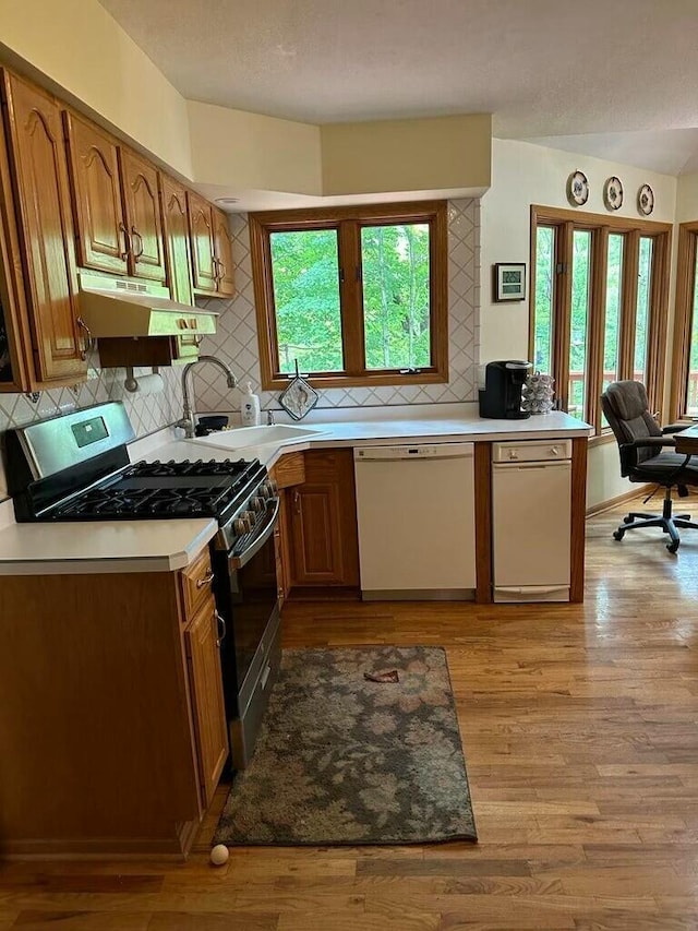 kitchen with a sink, under cabinet range hood, stainless steel range with gas cooktop, light wood finished floors, and dishwasher