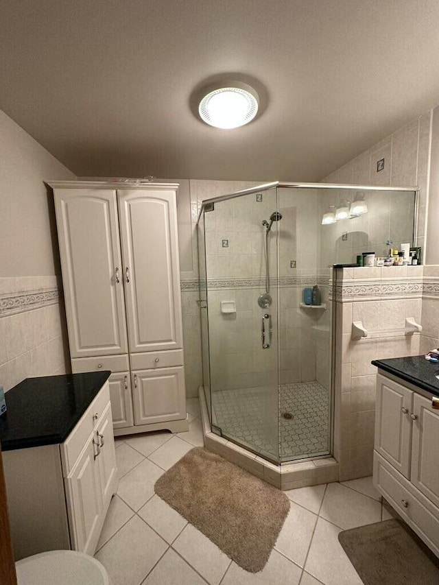 full bathroom featuring tile patterned floors, vanity, tile walls, and a shower stall