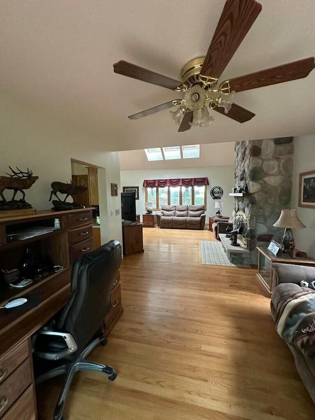 home office with light wood-style flooring, a fireplace, and a ceiling fan