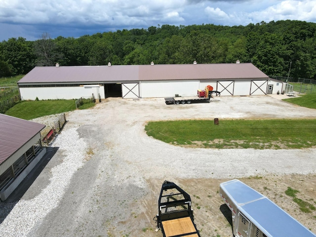 view of outdoor structure with an outbuilding, a wooded view, and driveway