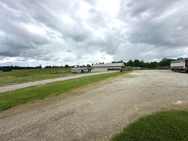 view of street featuring gravel driveway and a rural view