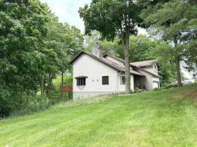 view of property exterior featuring an attached garage, a yard, and a chimney