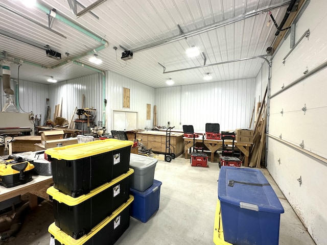 garage with a workshop area, a garage door opener, and metal wall