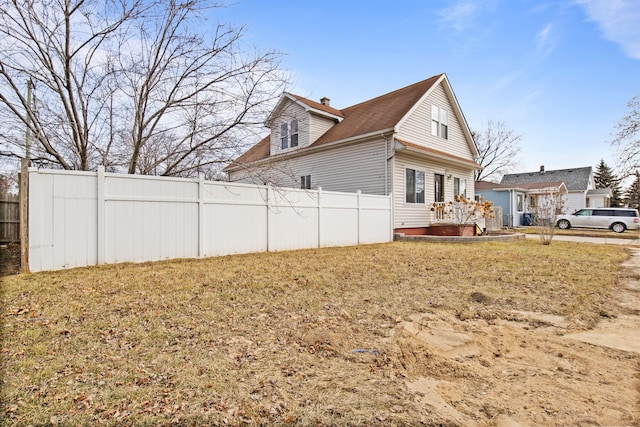 view of side of home featuring a lawn and fence