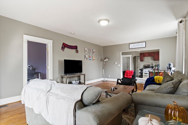 living room featuring visible vents, baseboards, and light wood-style flooring