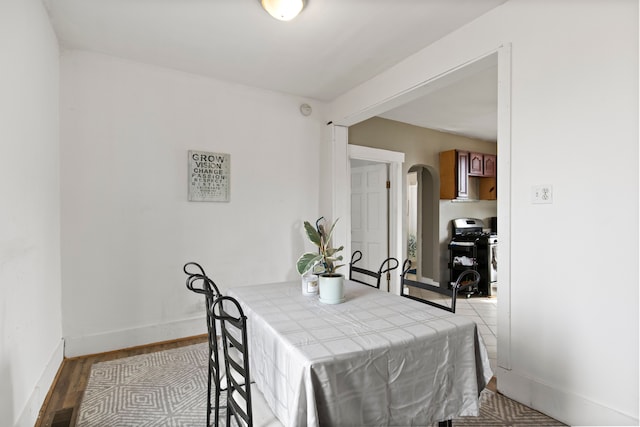 dining space featuring visible vents, light wood-style floors, arched walkways, and baseboards