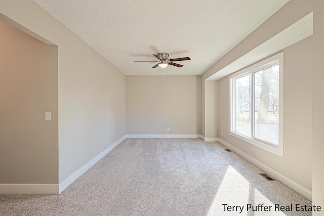 spare room featuring visible vents, baseboards, a textured ceiling, and light colored carpet