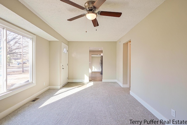 spare room with visible vents, light colored carpet, baseboards, and a textured ceiling