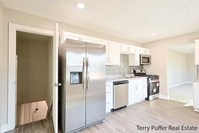 kitchen with a sink, decorative backsplash, appliances with stainless steel finishes, and white cabinets