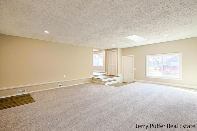 unfurnished room with visible vents, carpet, and a skylight