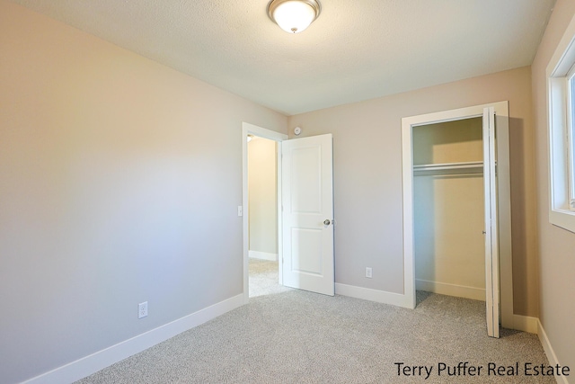 unfurnished bedroom featuring a closet, baseboards, a textured ceiling, and carpet flooring