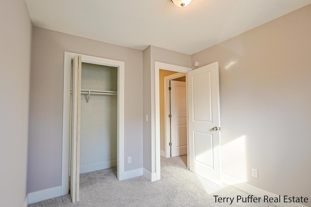 unfurnished bedroom with baseboards, a closet, and light carpet