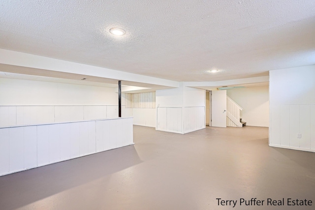 finished basement with stairway and a textured ceiling