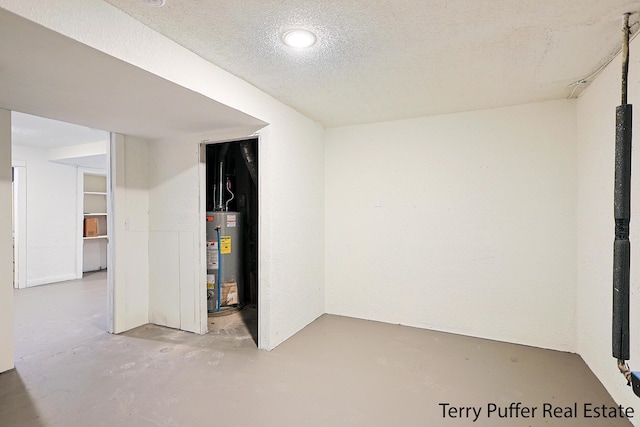 finished basement featuring a textured ceiling and water heater