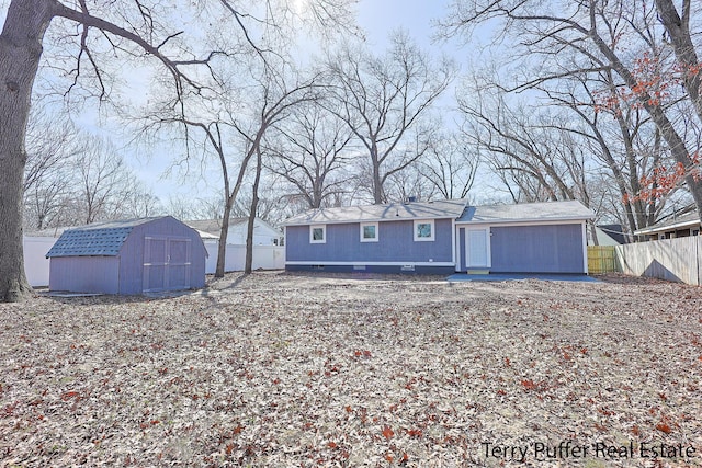 back of house featuring a storage unit, an outdoor structure, and fence