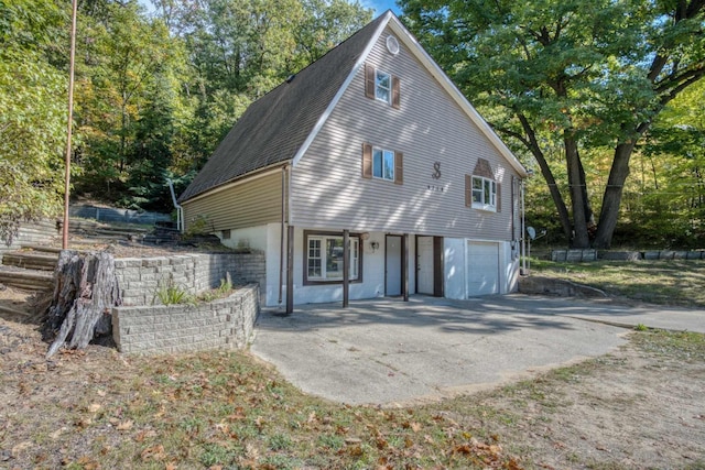 view of front of home featuring driveway, a shingled roof, and a garage