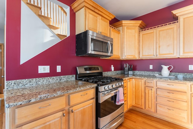 kitchen featuring light stone counters, light wood-type flooring, light brown cabinetry, and stainless steel appliances