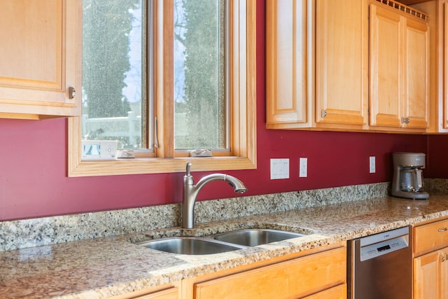 kitchen with dishwasher, light stone counters, light brown cabinets, and a sink