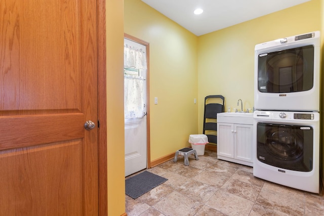 laundry room featuring a sink, cabinet space, baseboards, and stacked washing maching and dryer