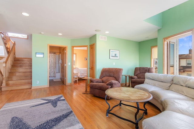 living area with visible vents, baseboards, light wood-type flooring, stairs, and recessed lighting