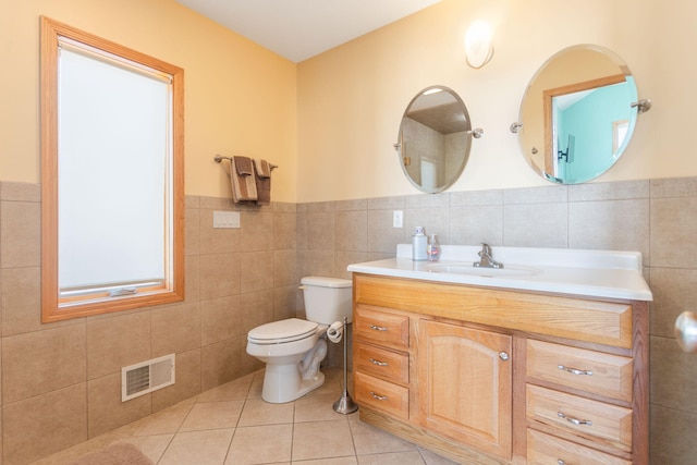 bathroom featuring vanity, visible vents, tile patterned floors, toilet, and tile walls