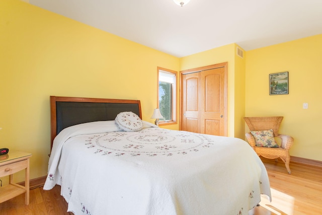 bedroom featuring wood finished floors, visible vents, a closet, and baseboards