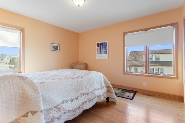 bedroom featuring visible vents, baseboards, and wood finished floors