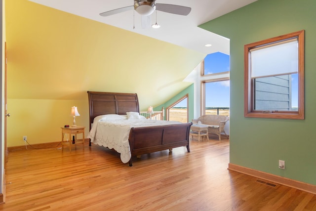 bedroom featuring visible vents, a ceiling fan, light wood finished floors, baseboards, and vaulted ceiling