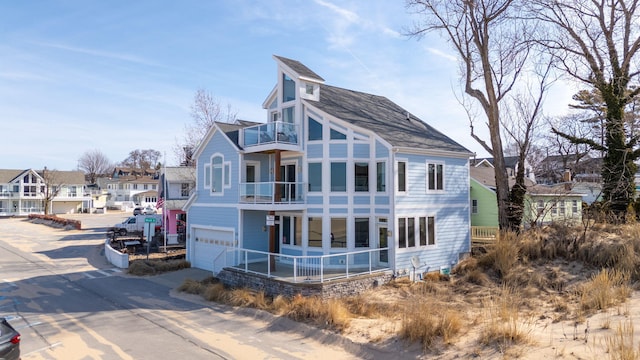 rear view of house featuring a residential view, an attached garage, driveway, and a balcony