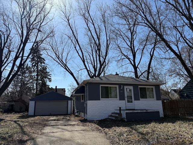 bungalow-style house with a garage, stone siding, an outbuilding, and fence