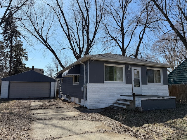 view of front of house with a detached garage, stone siding, an outdoor structure, and fence