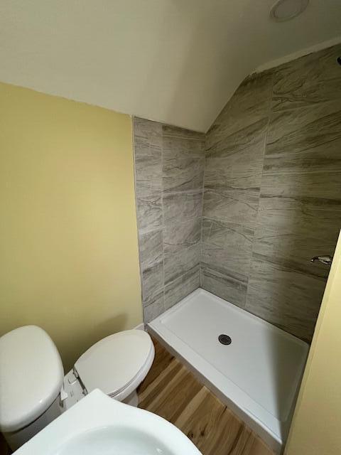 bathroom featuring a shower stall, toilet, lofted ceiling, and wood finished floors