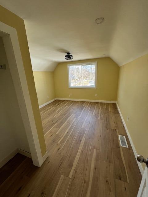 bonus room with visible vents, baseboards, wood finished floors, and vaulted ceiling