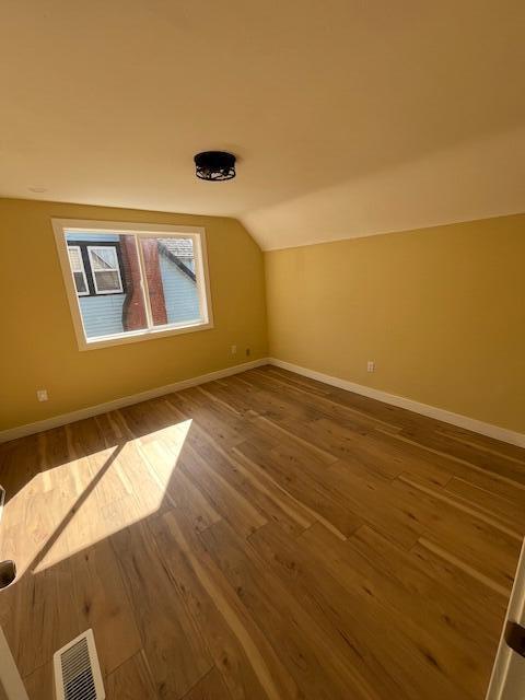 bonus room featuring visible vents, baseboards, wood finished floors, and vaulted ceiling