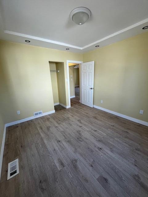 unfurnished bedroom with visible vents, baseboards, and wood finished floors