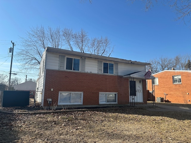 back of property with central AC unit and brick siding