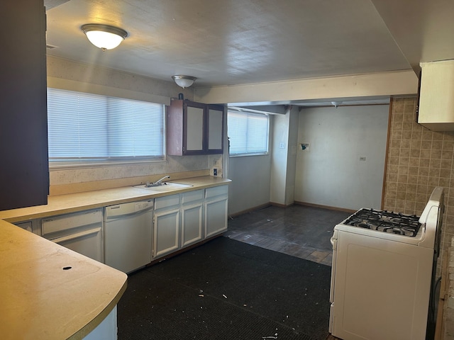 kitchen with baseboards, dark wood finished floors, light countertops, white appliances, and a sink