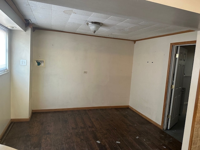 empty room featuring dark wood-style flooring, baseboards, and ornamental molding