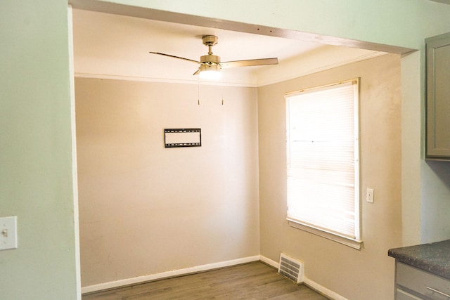 interior space featuring ceiling fan, visible vents, baseboards, and wood finished floors