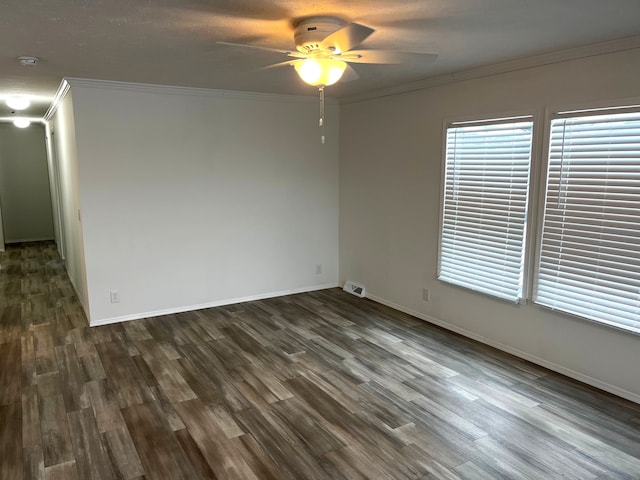 spare room with ceiling fan, dark wood-type flooring, visible vents, and ornamental molding