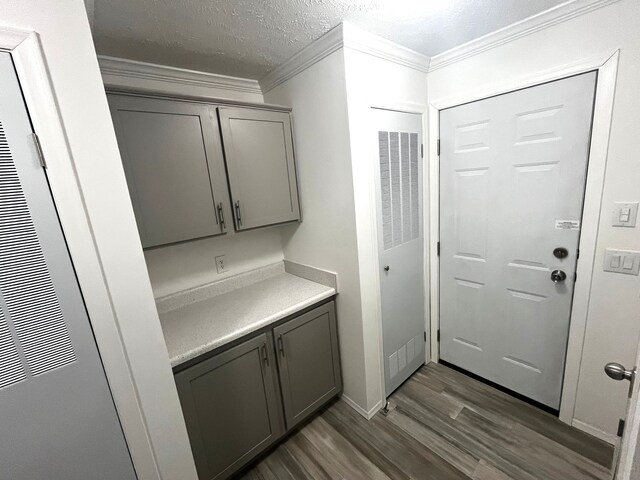 laundry area featuring dark wood finished floors, a textured ceiling, a heating unit, and ornamental molding