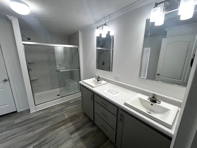 bathroom with double vanity, ornamental molding, a stall shower, and a sink