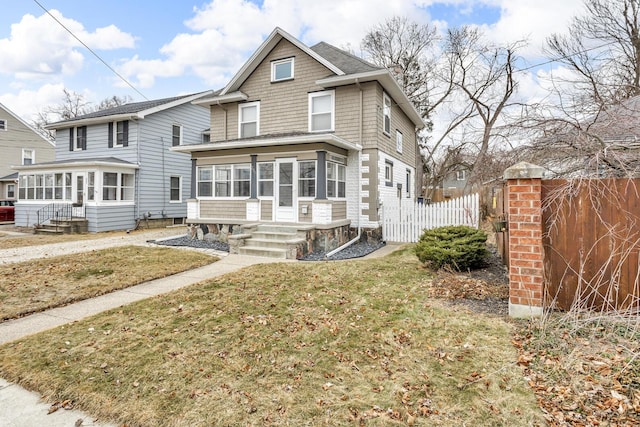 view of front facade featuring fence, a front yard, and a sunroom