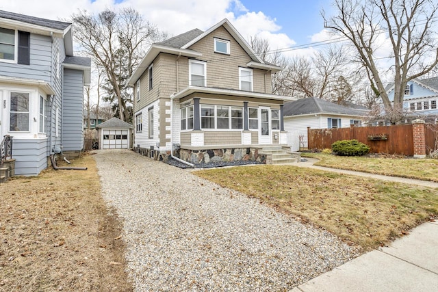 view of front facade with a garage, an outbuilding, driveway, and fence