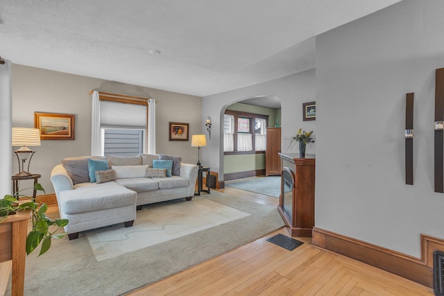 living area with baseboards, arched walkways, and hardwood / wood-style floors